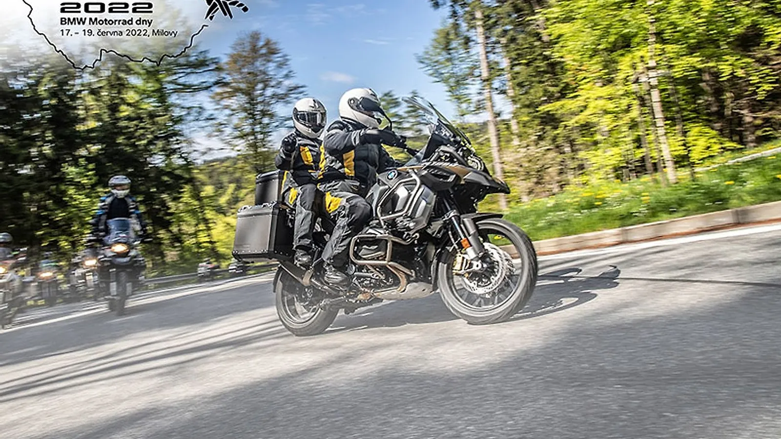 Dvojice na motorce BMW R 1250 GS Adventure v zatáčce lesní silnice, vizuál BMW Motorrad dnů 2022 v Milovech