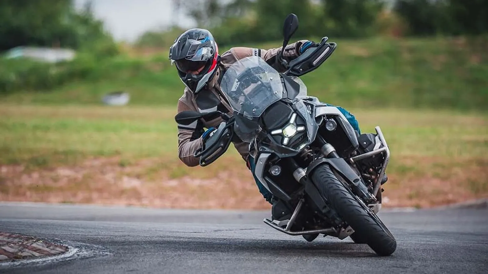 Jezdec na motorce BMW GS v hlubokém náklonu v zatáčce asfaltového okruhu