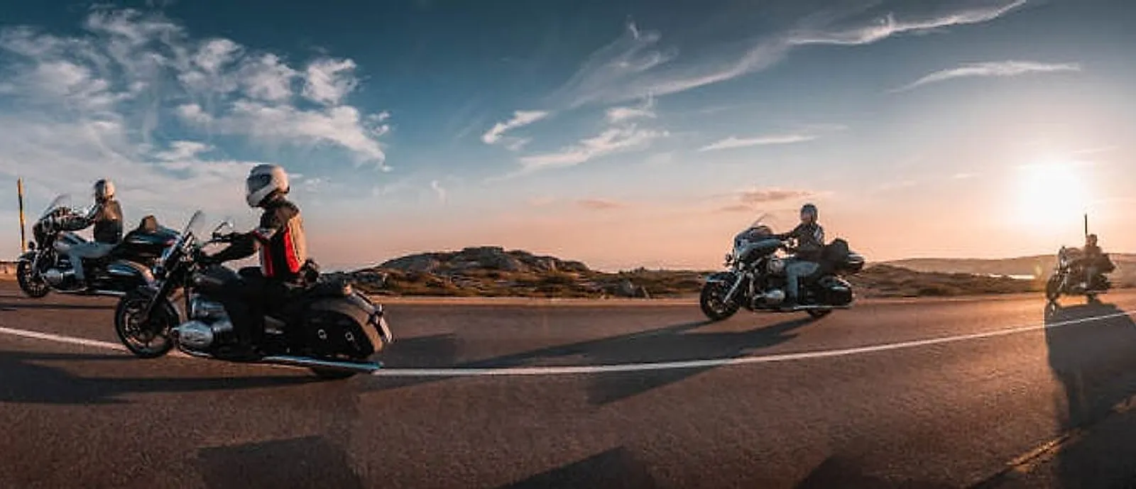 Skupina motorkářů na cruiserech BMW R18 na portugalské silnici při západu slunce
