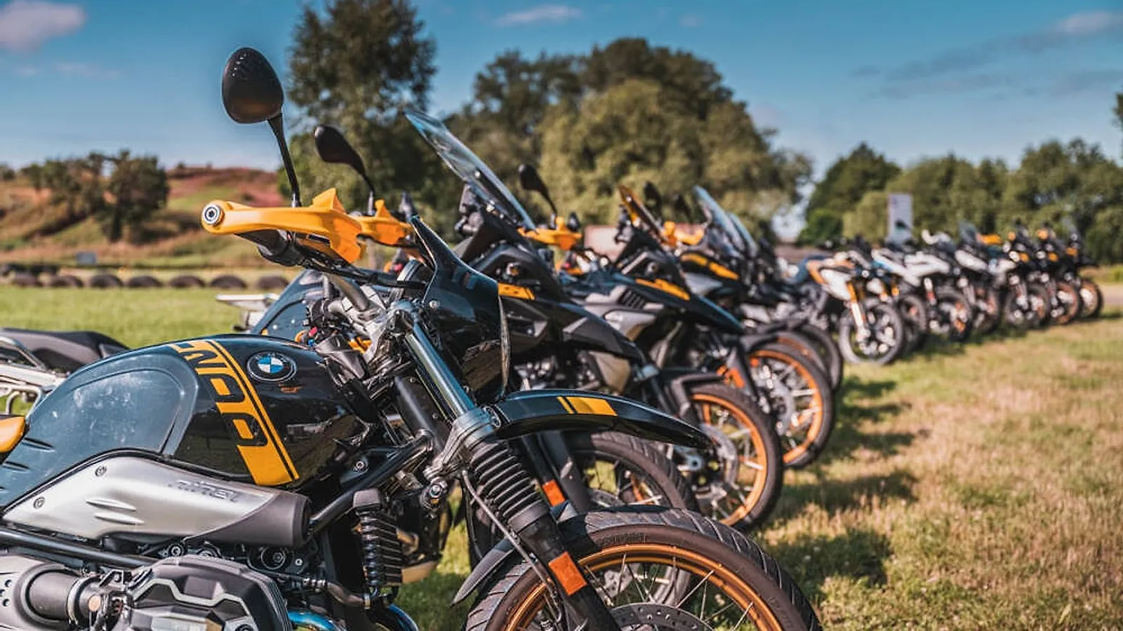 Řada motorek BMW R nine T a GS zaparkovaná v trávě, připravená k zapůjčení