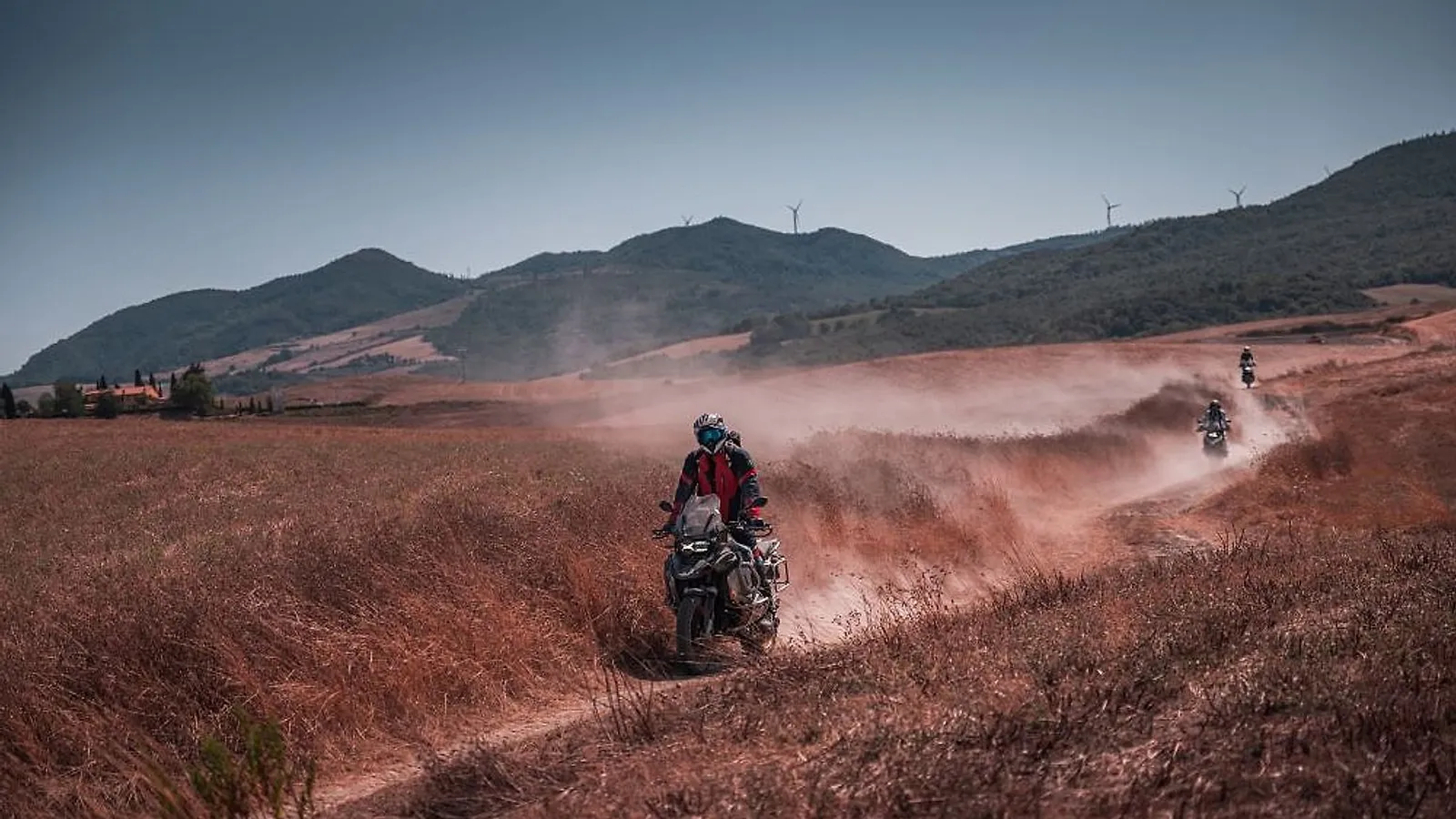 Jezdec na motorce BMW GS na šotolinové cestě v italských kopcích