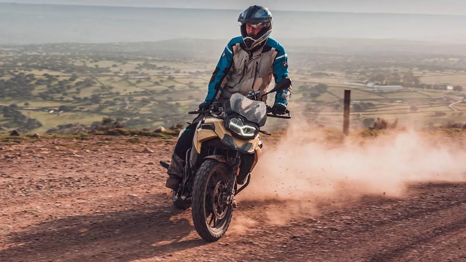 Jezdec na BMW F 850 GS zvedá prach na šotolinové cestě nad krajinou španělské Extremadury