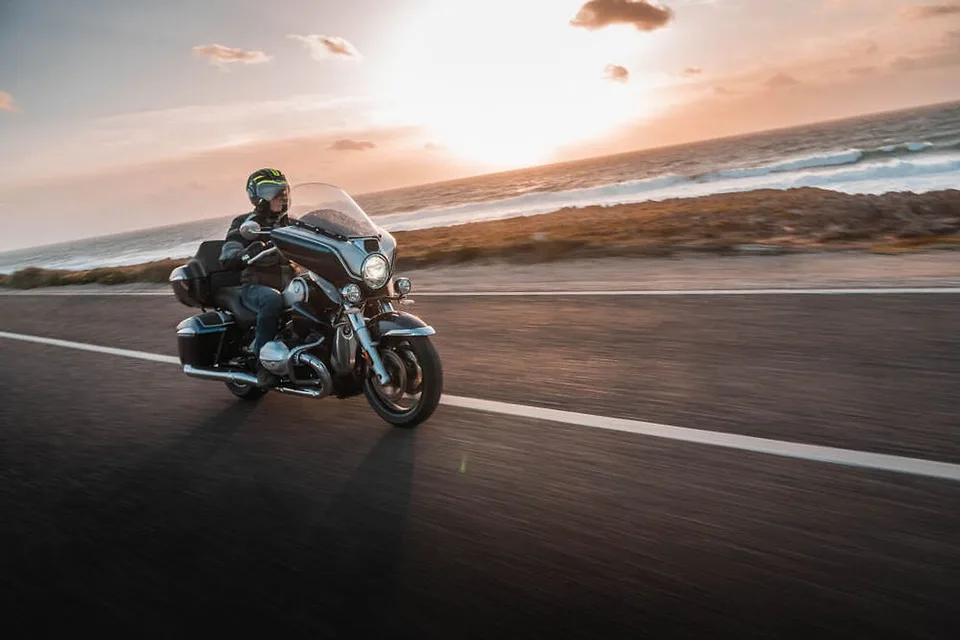 Cruiser BMW R 18 s kapotáží na pobřežní silnici při západu slunce