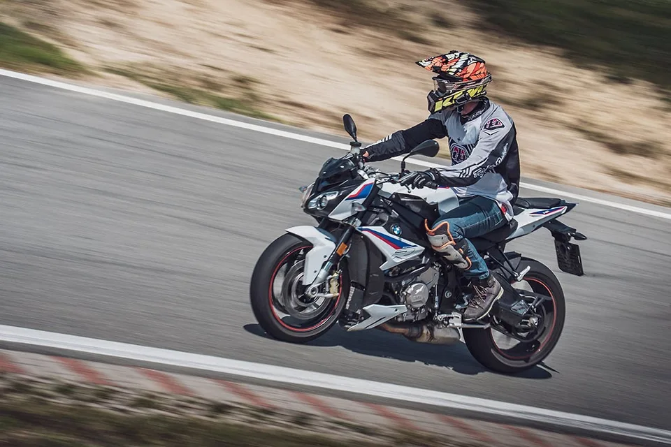 Jezdec v náklonu na modré BMW GS v zatáčce okruhu s travnatým okolím